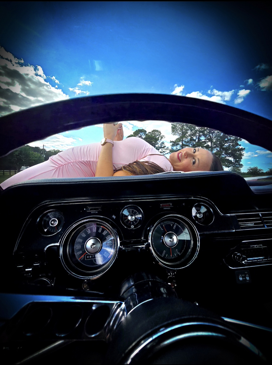 Looking through Reba Lou's steering wheel to the pink hood beyond.