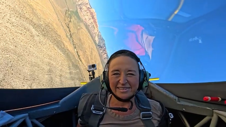 Nikki grinning in an aerobatic cockpit over the canyon.