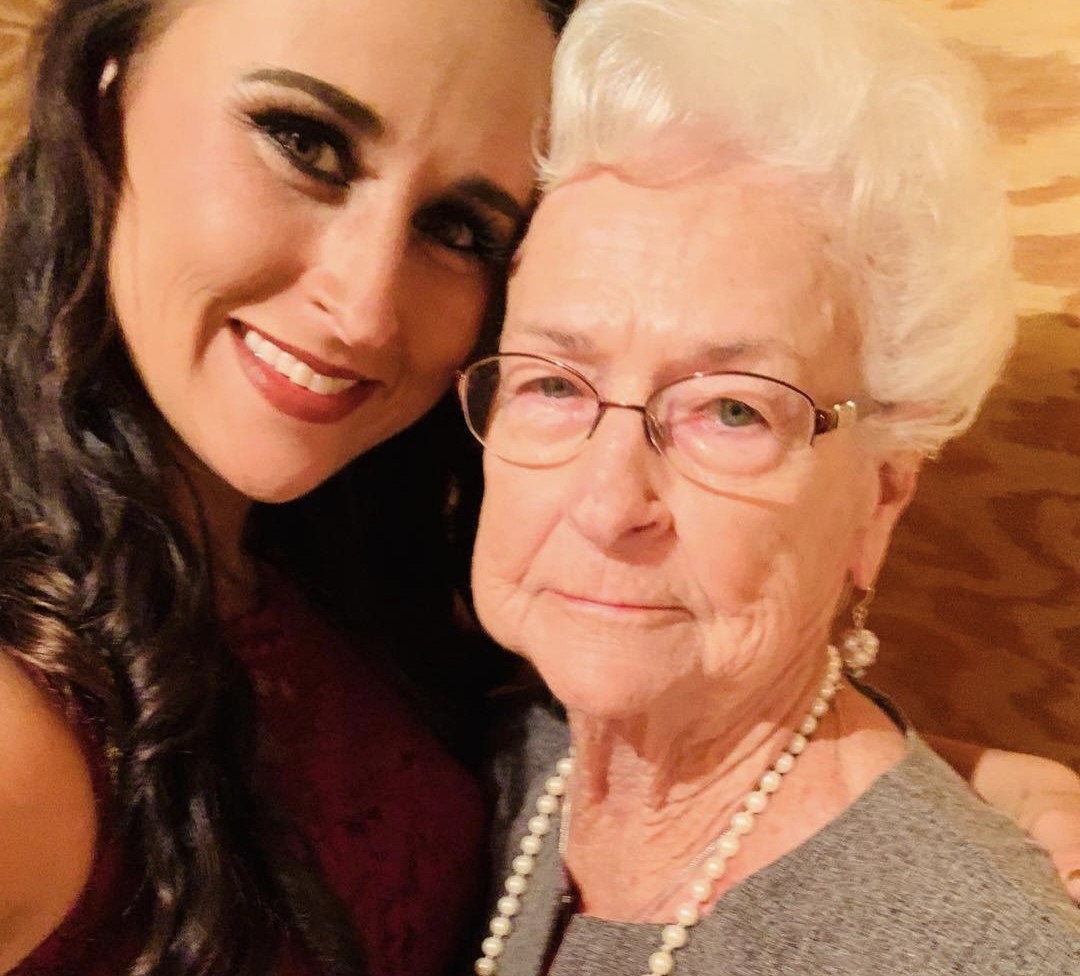 Nikki cheek to cheek with Grandma Reba, white-haired, in glasses and pearls.