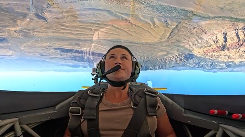 Nikki inverted over the desert in an aerobatic airplane.