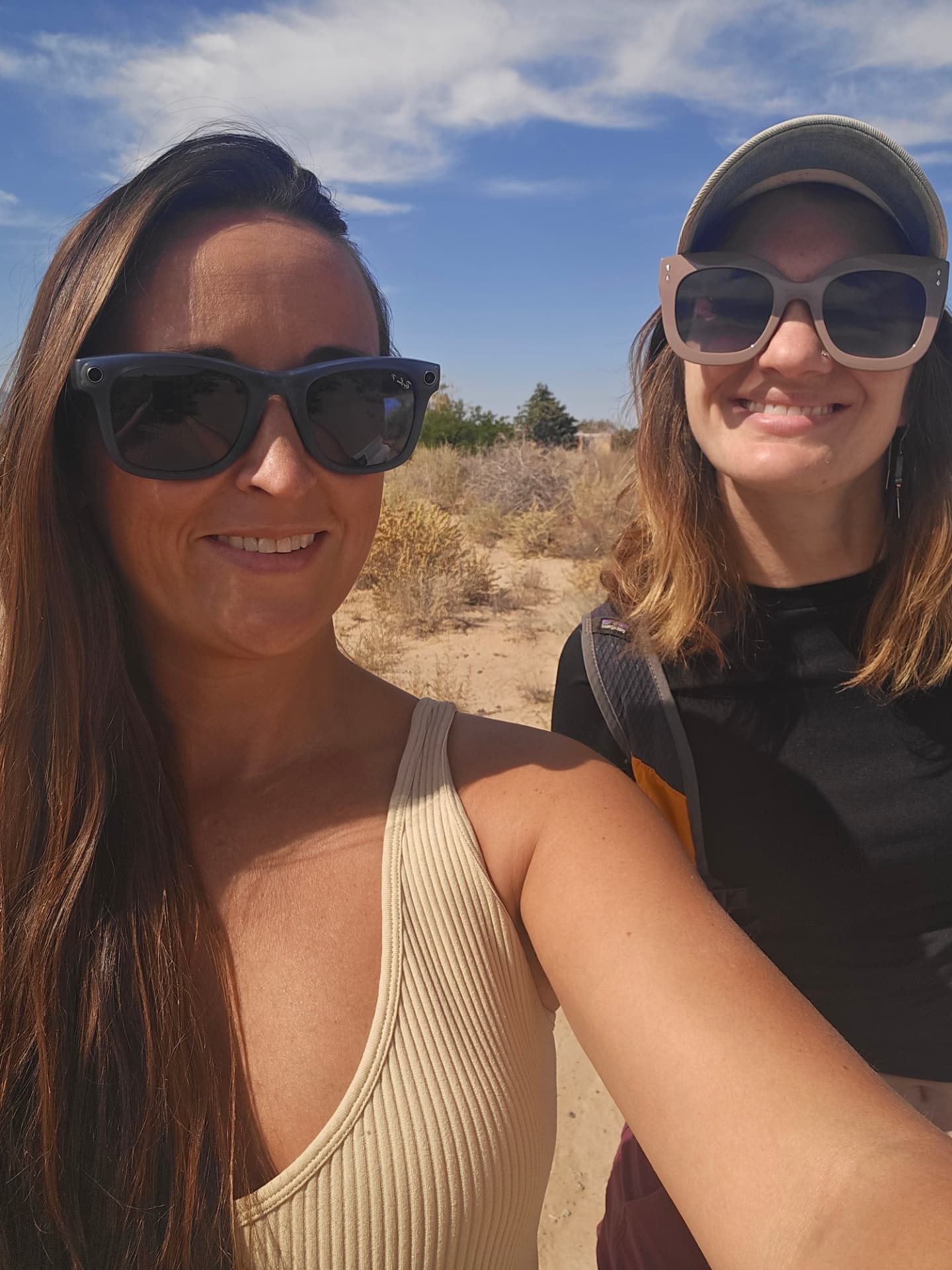 Nikki and Ali smiling in sunglasses in the high desert.