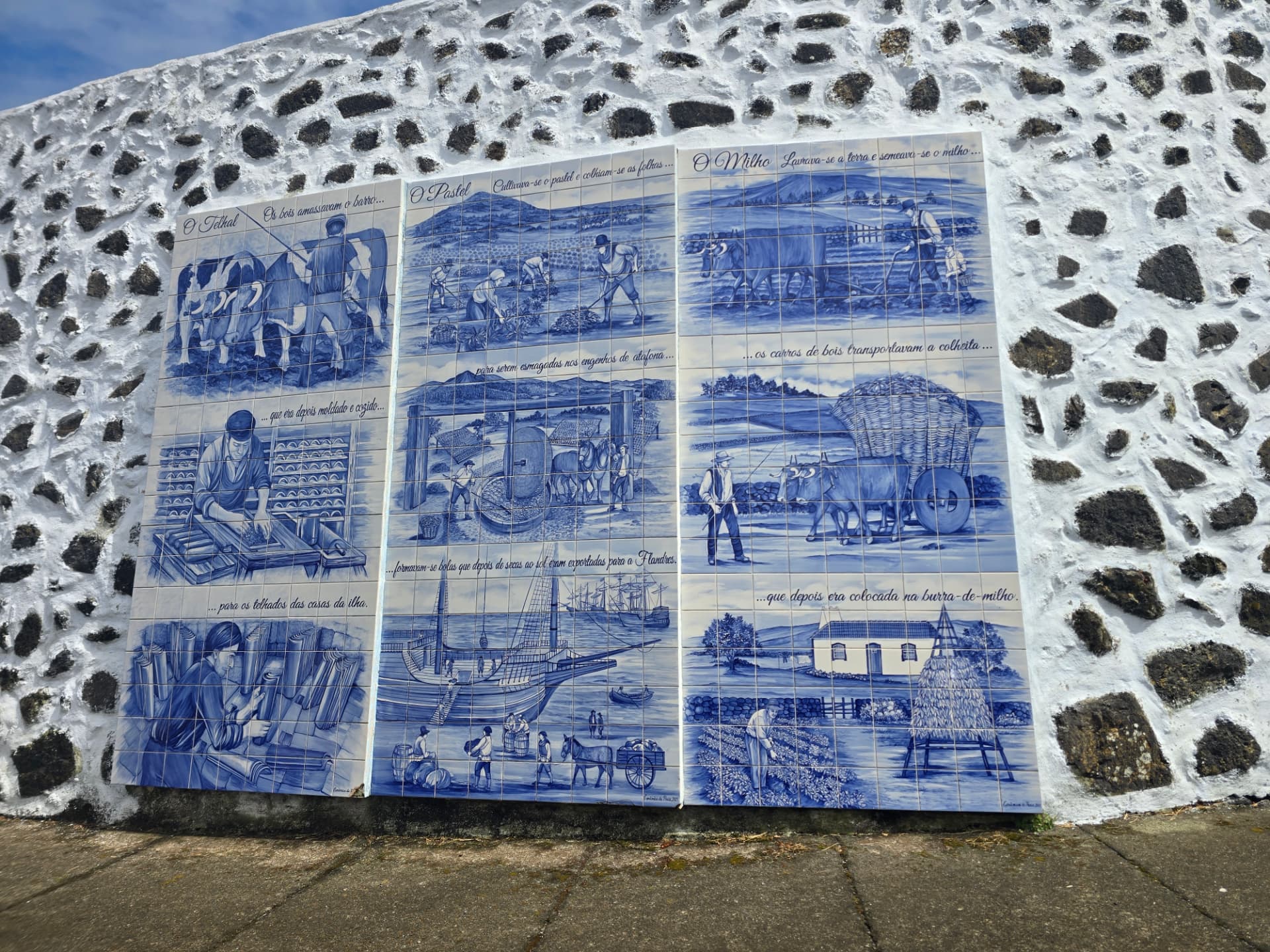 Blue-and-white azulejo panels of island farming history on a stone wall.