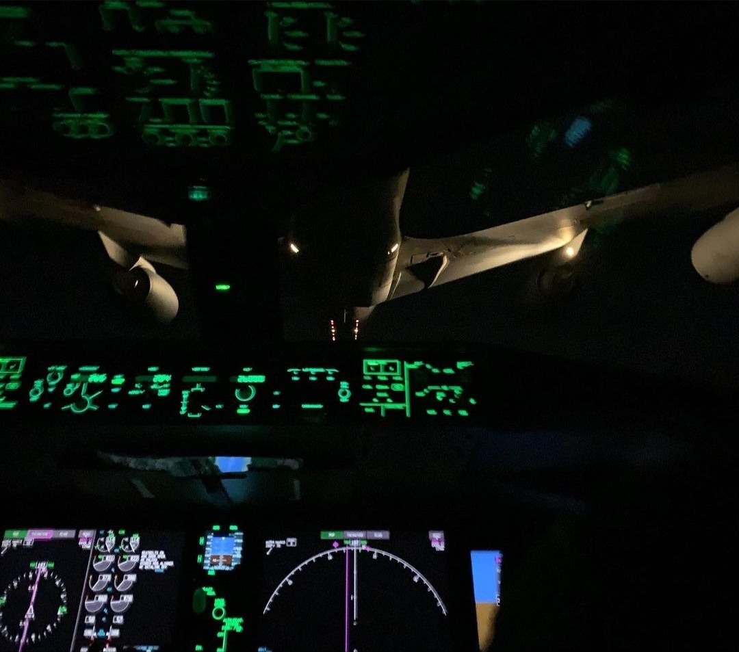 Night refueling behind a tanker, the cockpit lit green.