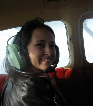 Nikki smiling back over her shoulder in a headset on her first flight with Brian.