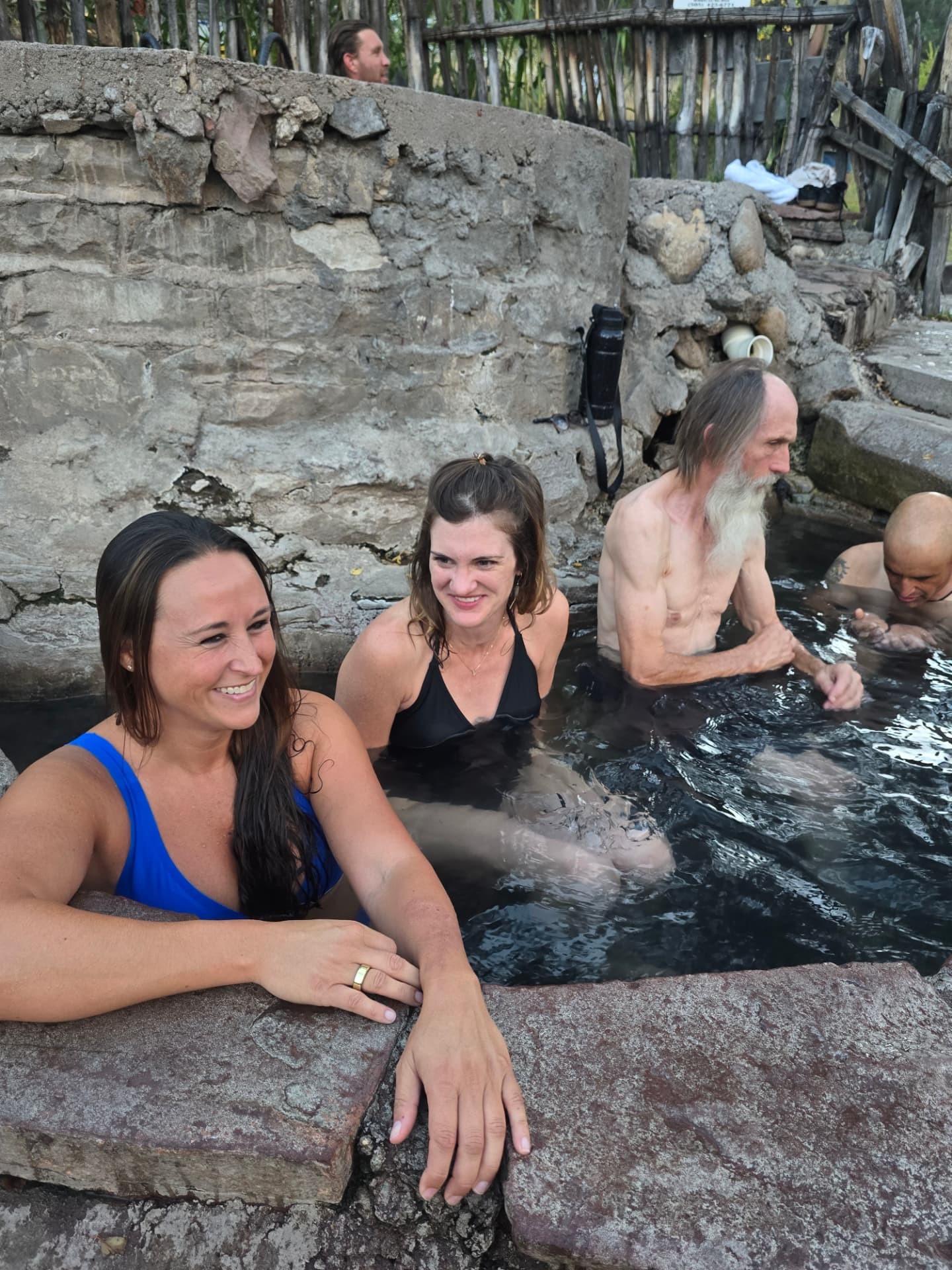 Nikki and Ali in a stone hot spring beside older men soaking.