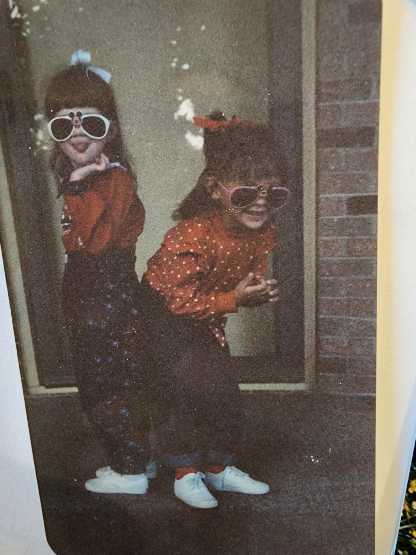 Nikki and Ali as little girls in oversized white sunglasses and matching outfits.