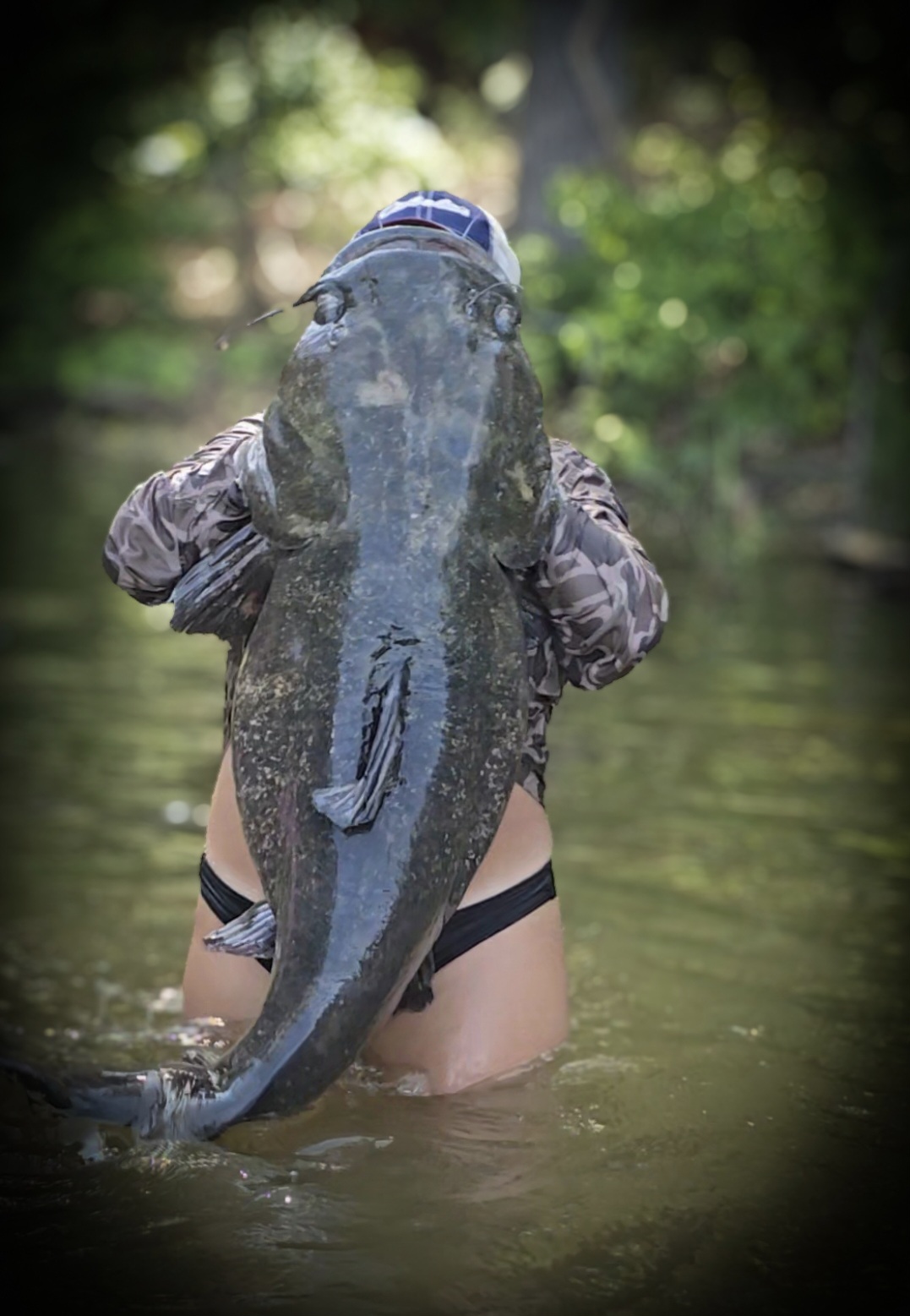 A giant catfish held up so tall it hides Nikki's face.