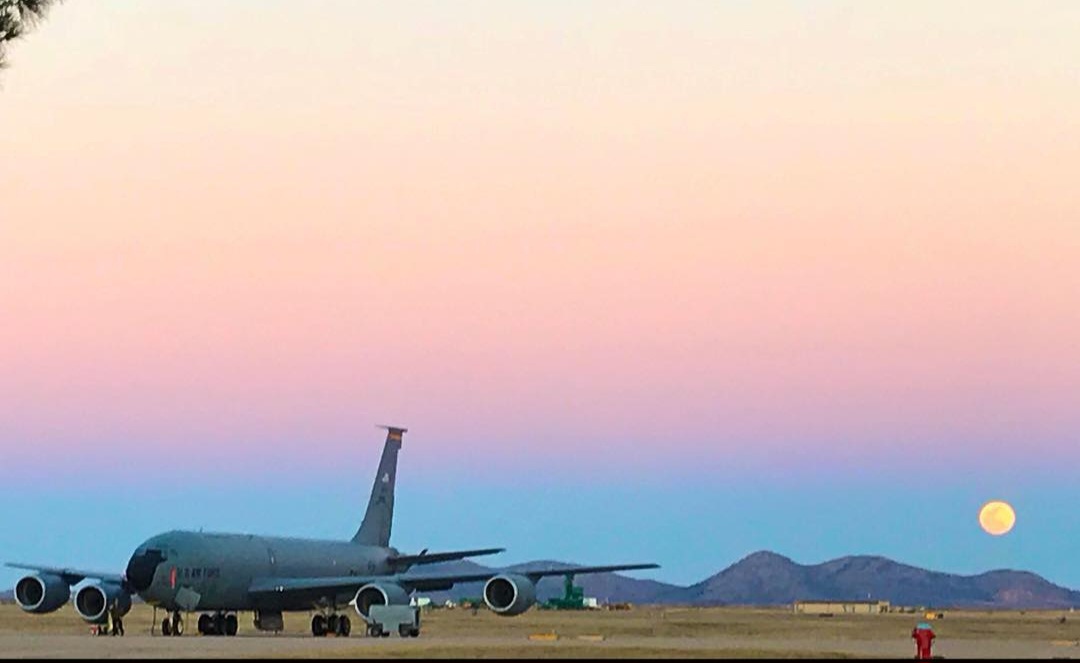 A KC-135 on the ramp at dusk, full moon rising over the mountains.
