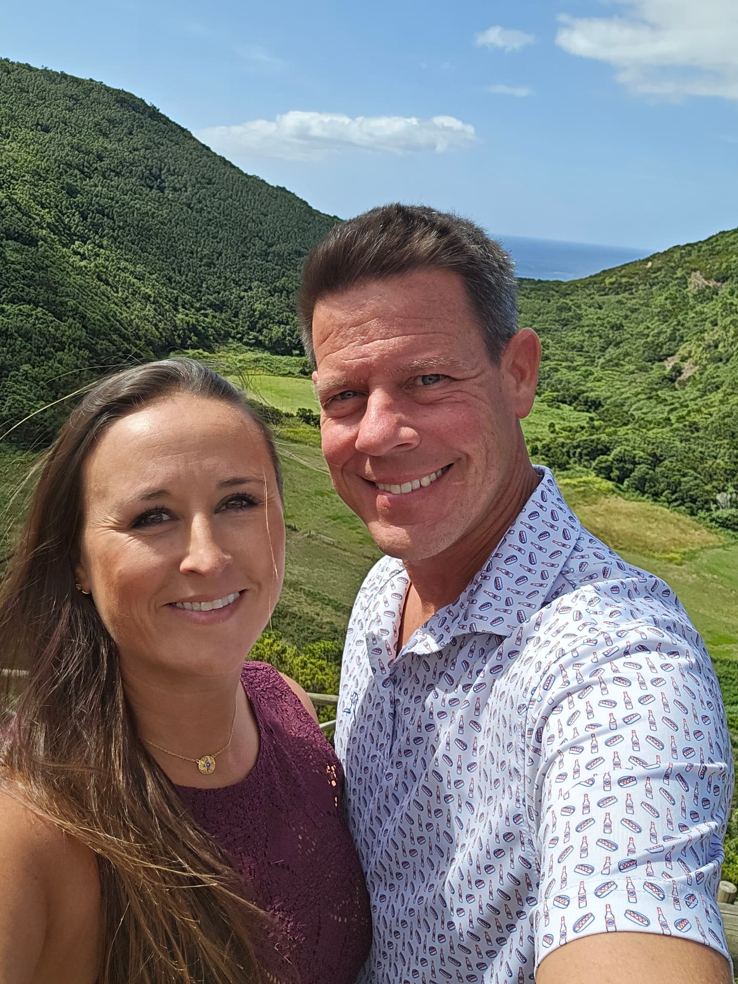 Nikki and Q smiling above a green valley.