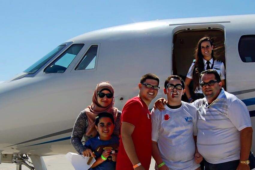 Nikki in the doorway of a jet above a smiling family at a charity event.