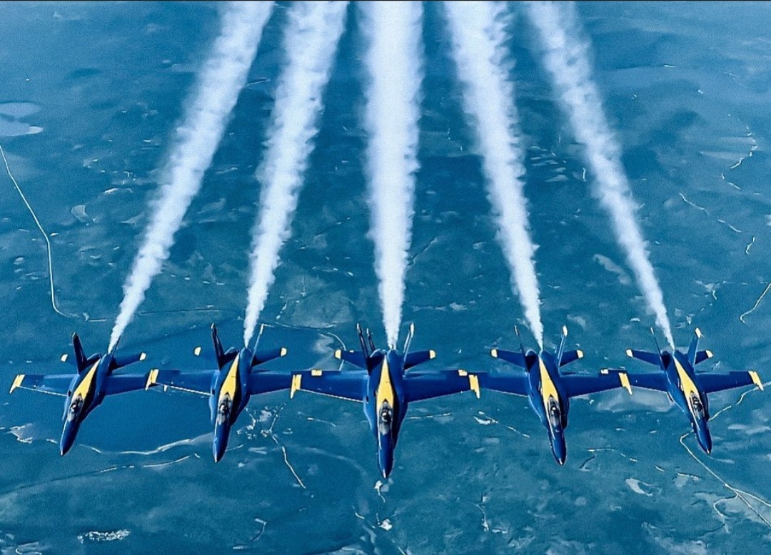 Five Blue Angels in line abreast, smoke trails streaming behind them.
