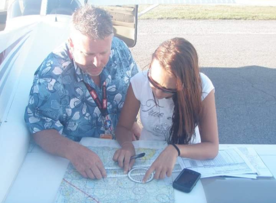 Nikki and her flight instructor planning a route over a sectional chart on the wing.
