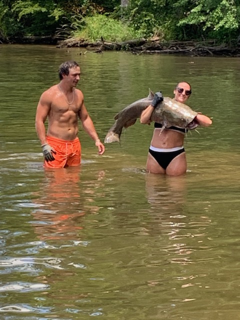 Nikki holding a big catfish across her chest as Slayter stands nearby.
