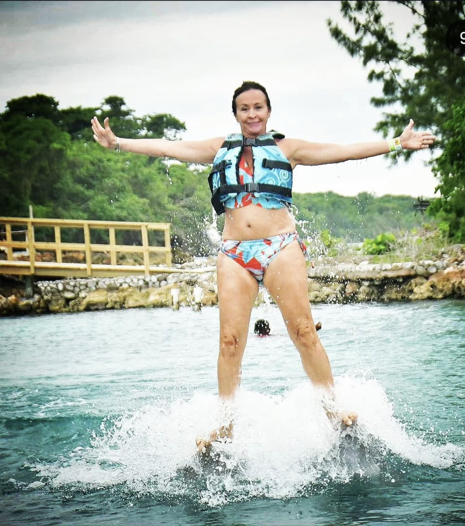 Patti rising out of the water on the dolphins, arms spread wide.