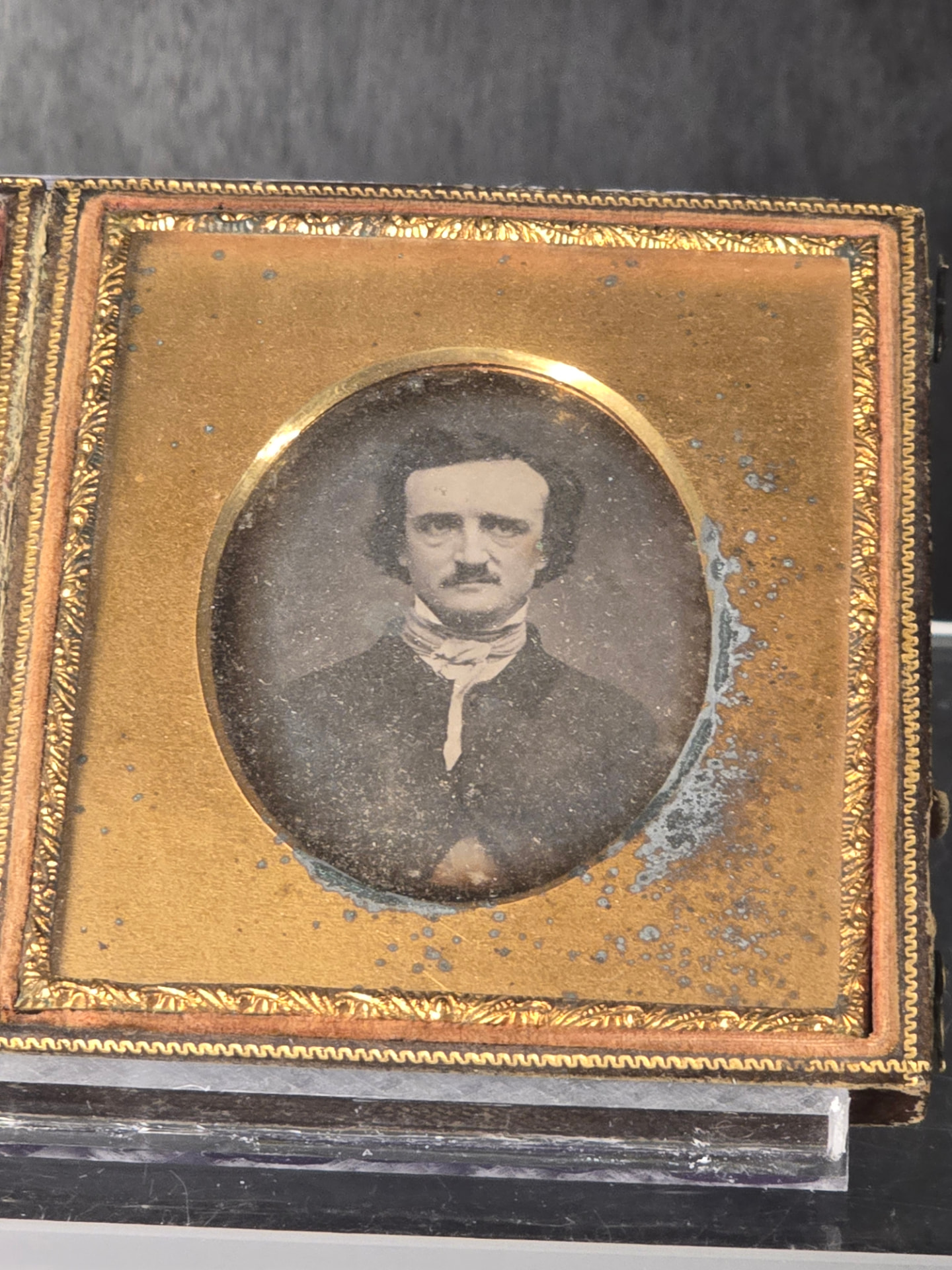 A cased daguerreotype of Edgar Allan Poe in an oval gilt mat, the silvered plate tarnishing at its edge.