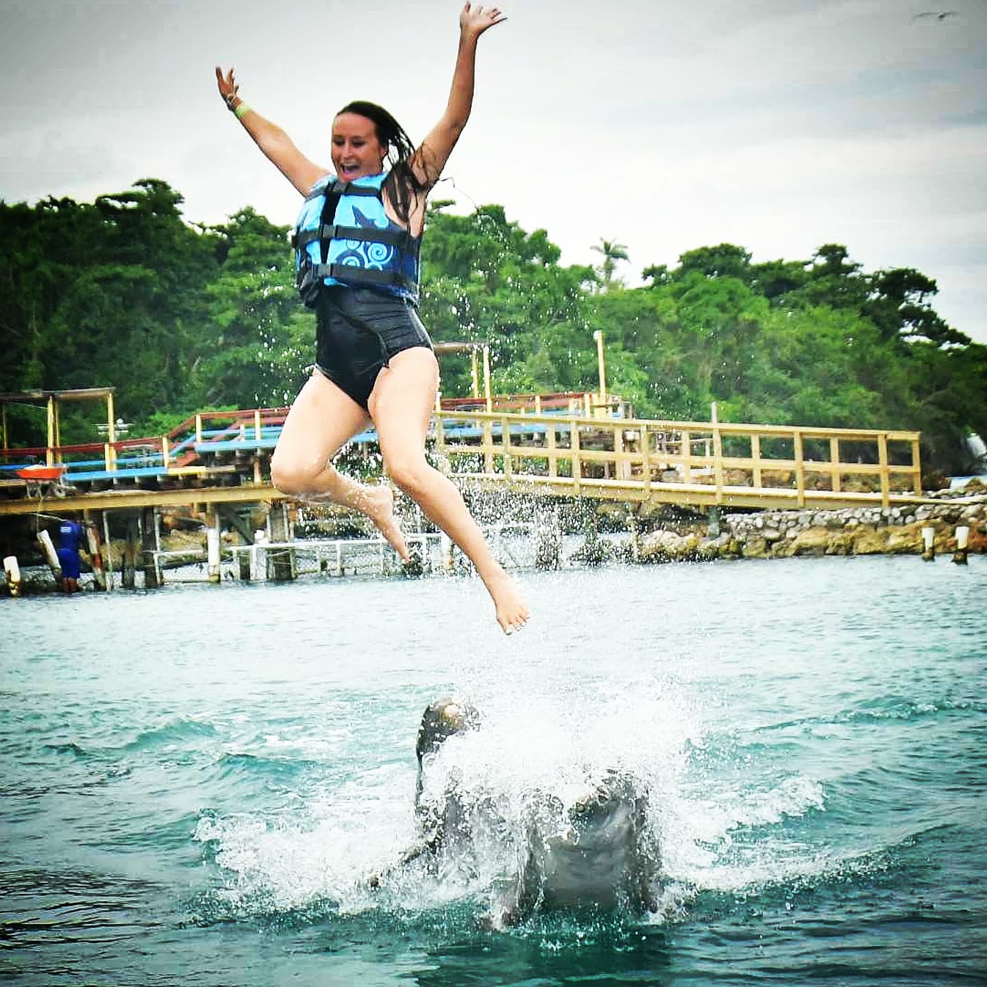 Nikki leaping high above the splash, arms raised.