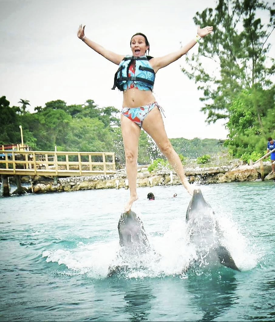 Patti leaping off the dolphins, one leg kicked up.