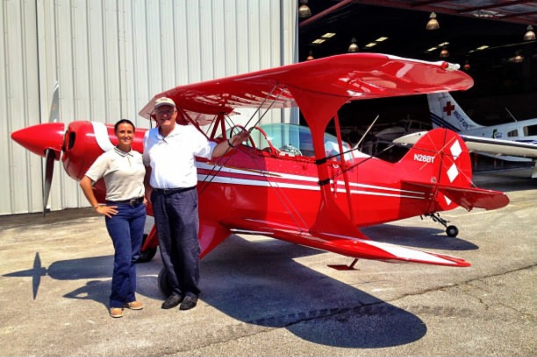 Nikki with Pete Pilcher beside his red Pitts biplane outside the hangar.