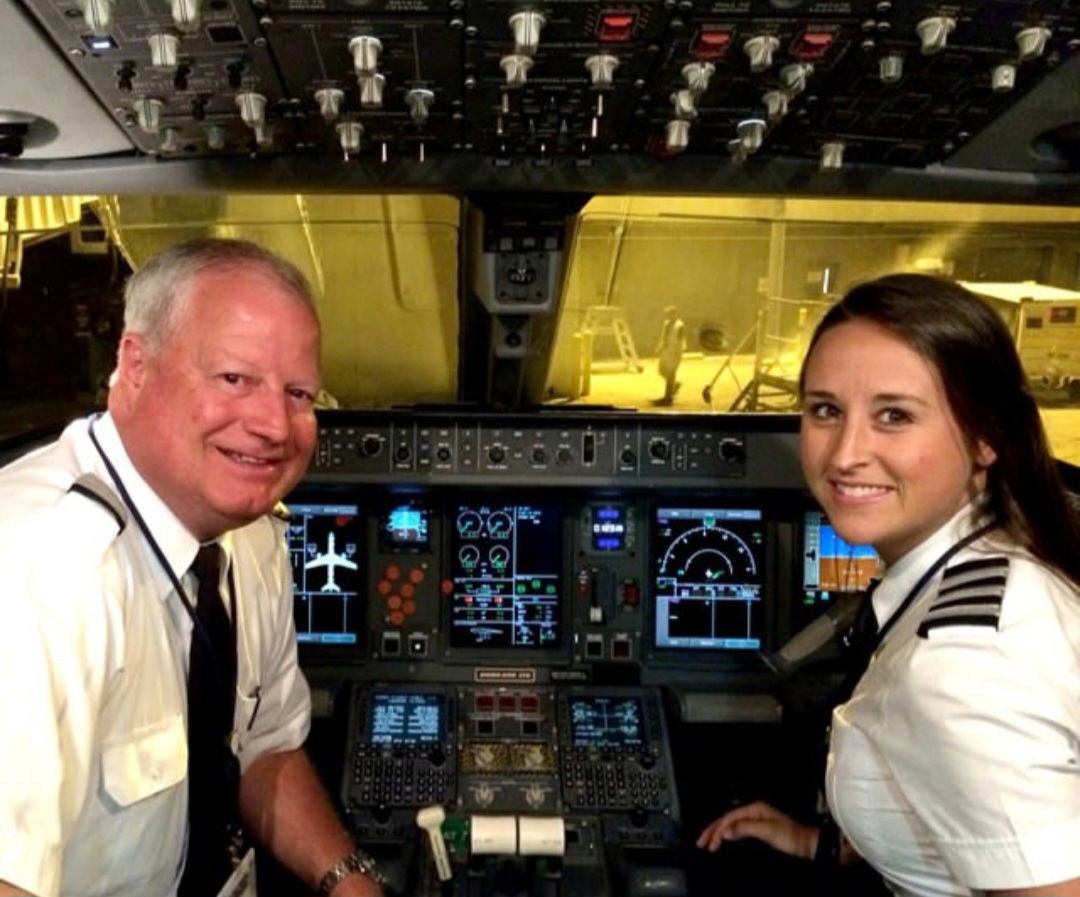 Nikki in uniform with a captain in the Embraer cockpit.