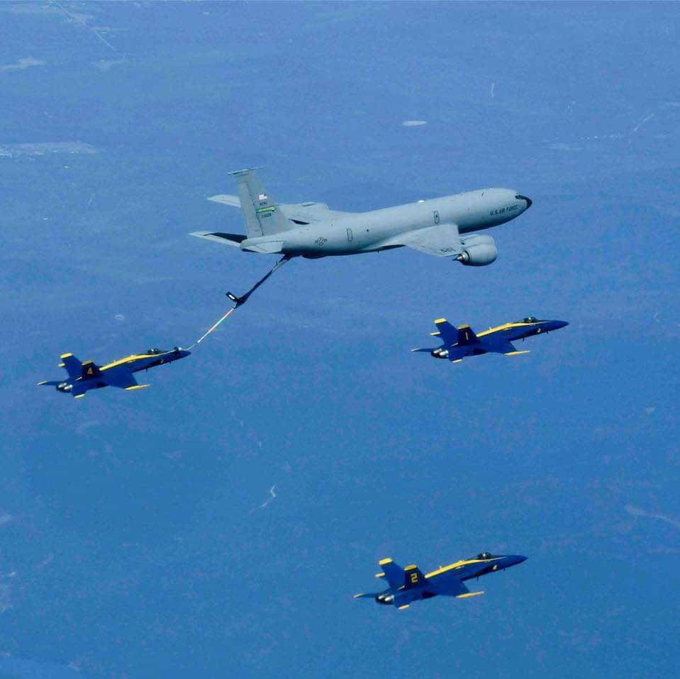 A KC-135 refueling the Blue Angels over open country.