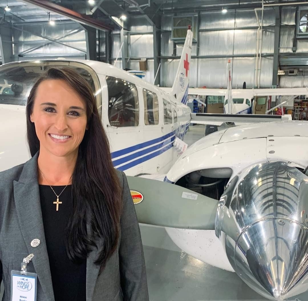 Nikki in the Wings of Hope hangar beside a medical-mission Piper.