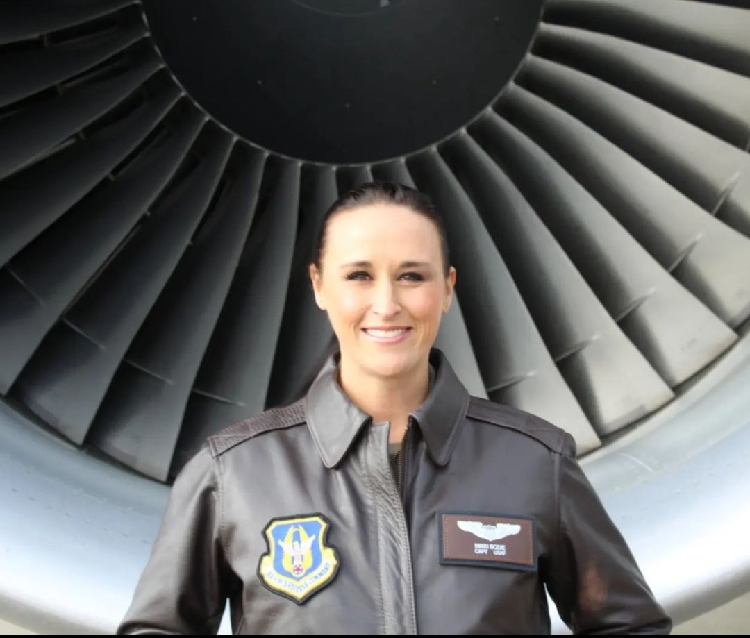 Nikki in her leather flight jacket in front of a jet engine's fan blades.