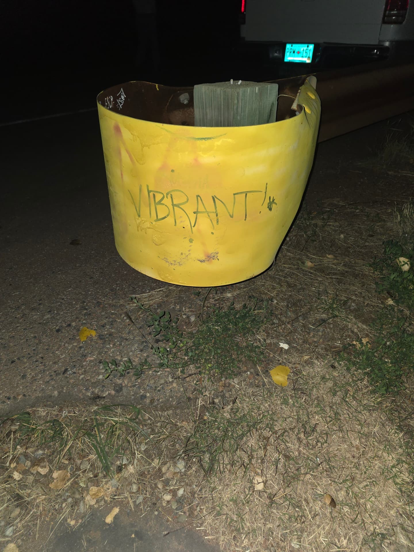 A yellow guardrail end at night with VIBRANT! written across it.