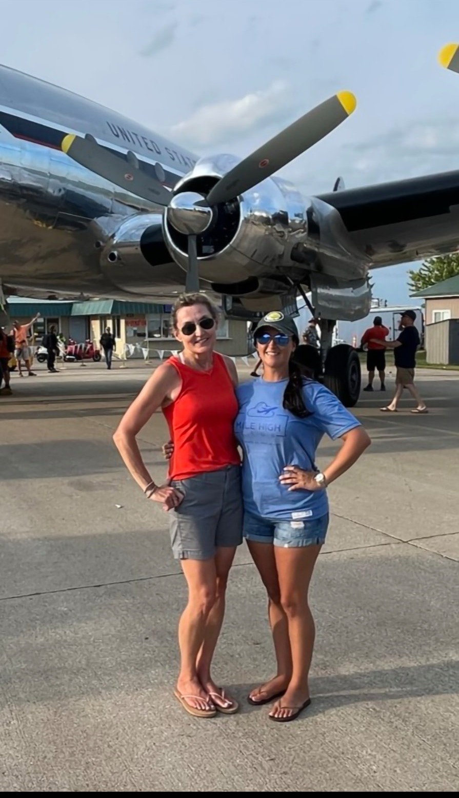 Nikki with her good friend Susanna in front of a silver propliner at an air show.