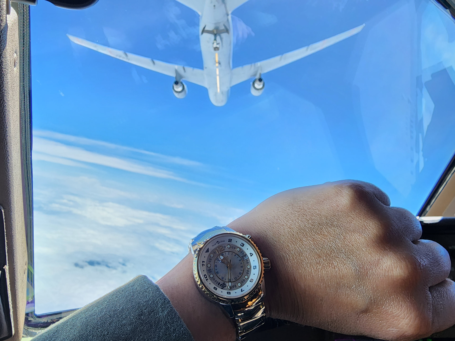 Nikki's watch on her wrist with a tanker overhead during refueling.