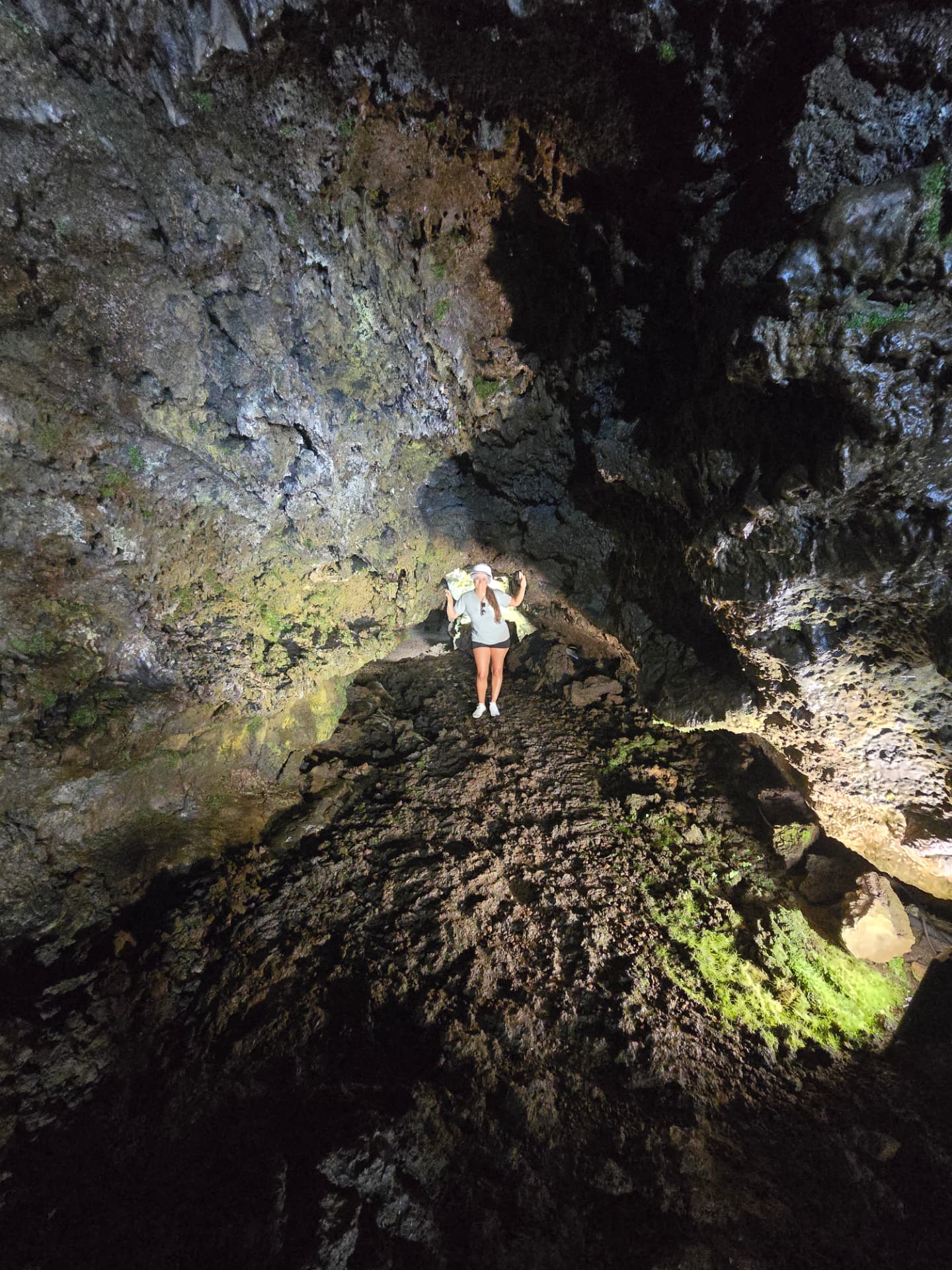 Nikki small against the rock inside a dark lava tube.