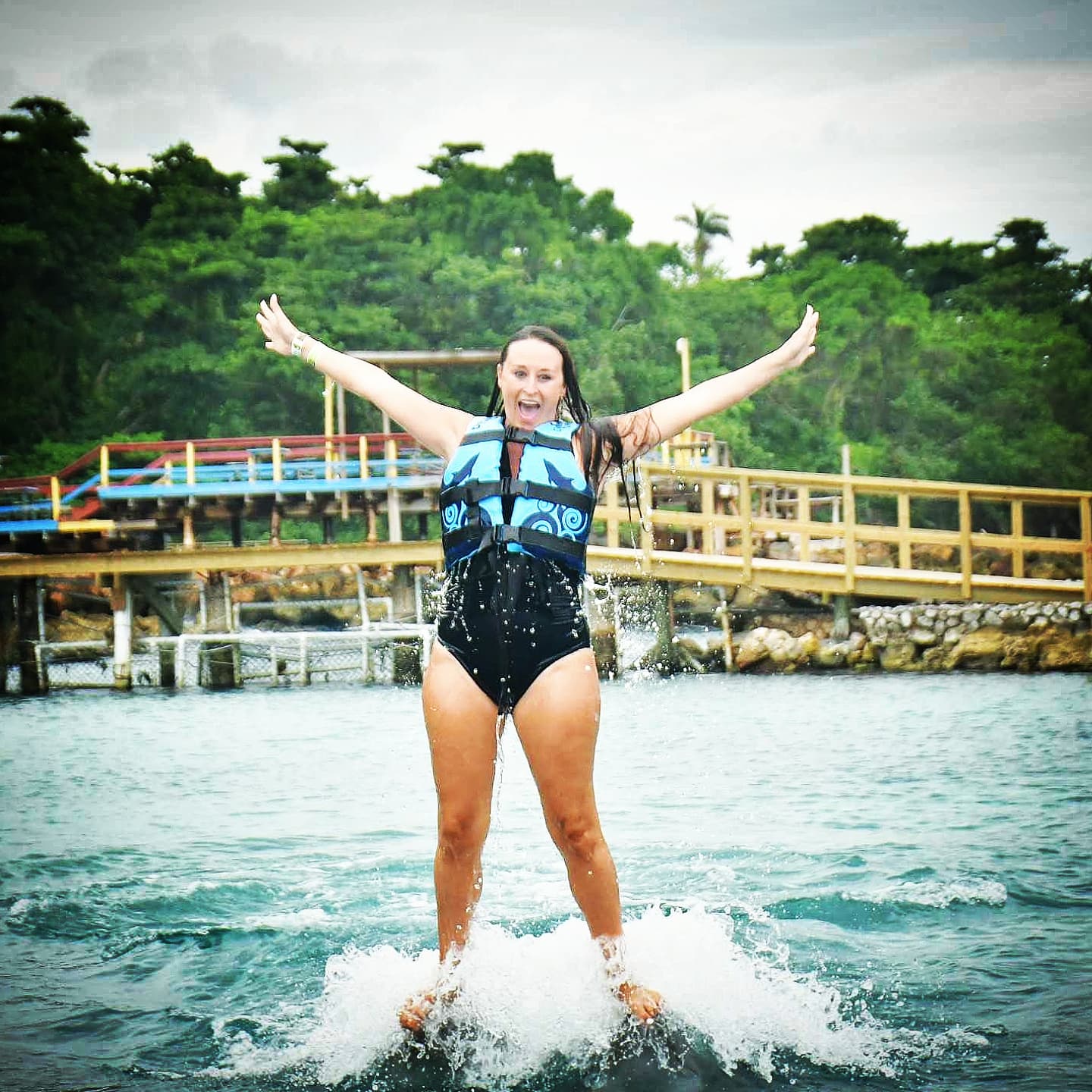 Nikki rising out of the water on the dolphins, arms spread wide.