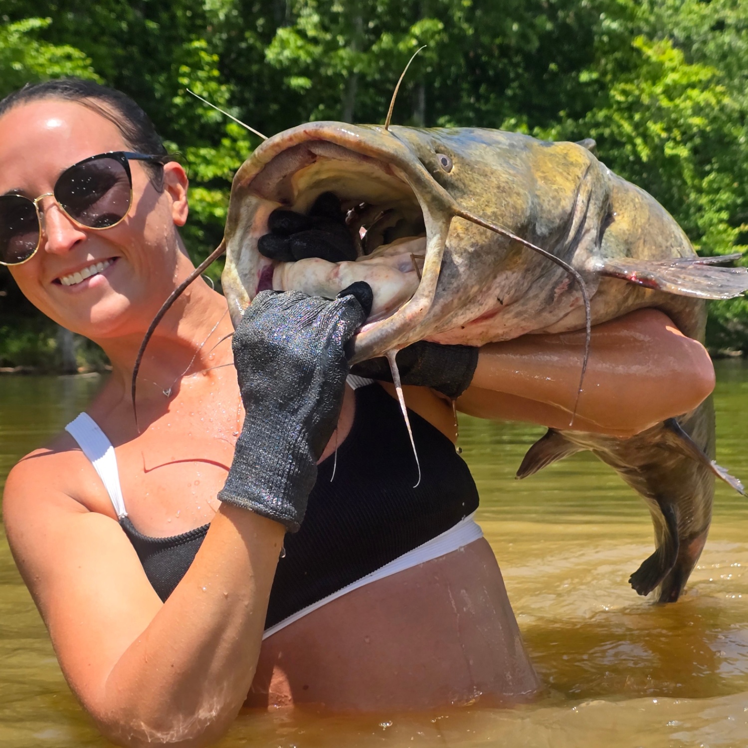 Nikki smiling with her gloved hand inside a giant catfish's mouth.