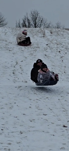 Two sleds carrying family members down a snowy Wisconsin hill.