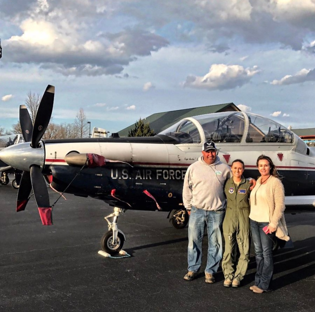 Nikki in her flight suit with Ty Daddy and her mom Patti beside a T-6.