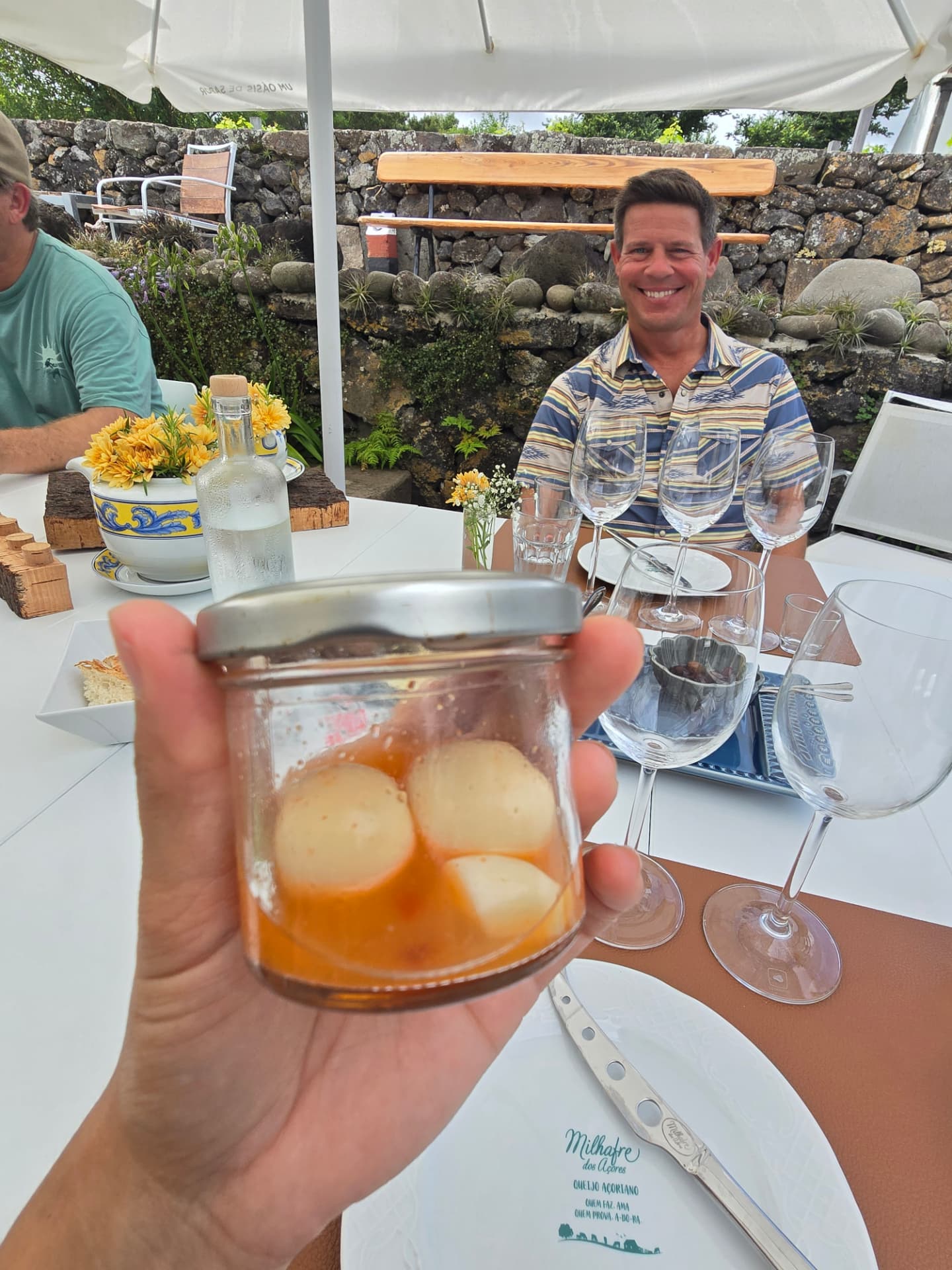 Cheese in a small jar held up at a lunch table.