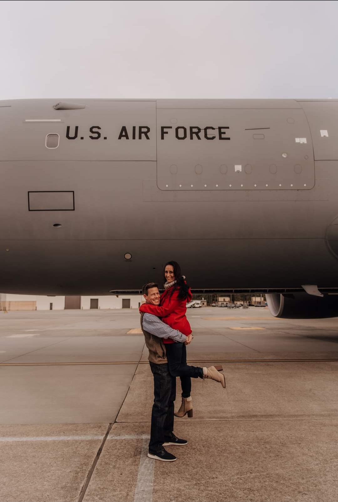Nikki lifted in a hug beneath a U.S. Air Force tanker.