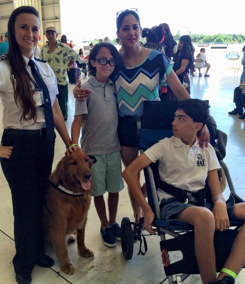 Nikki in uniform with a family and a golden retriever at a charity flying event.