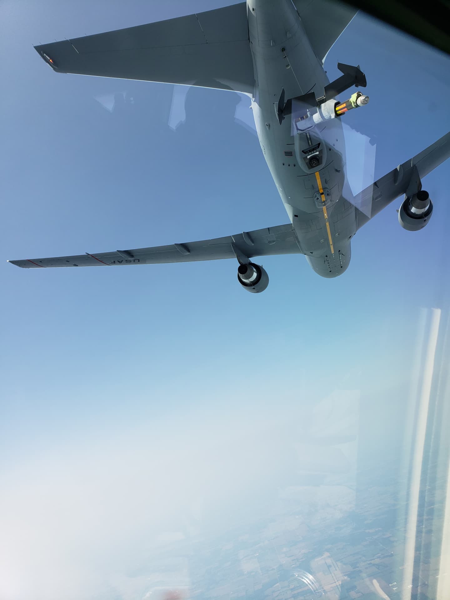 A USAF KC-46 directly overhead, its boom extended, as seen from the receiving jet.