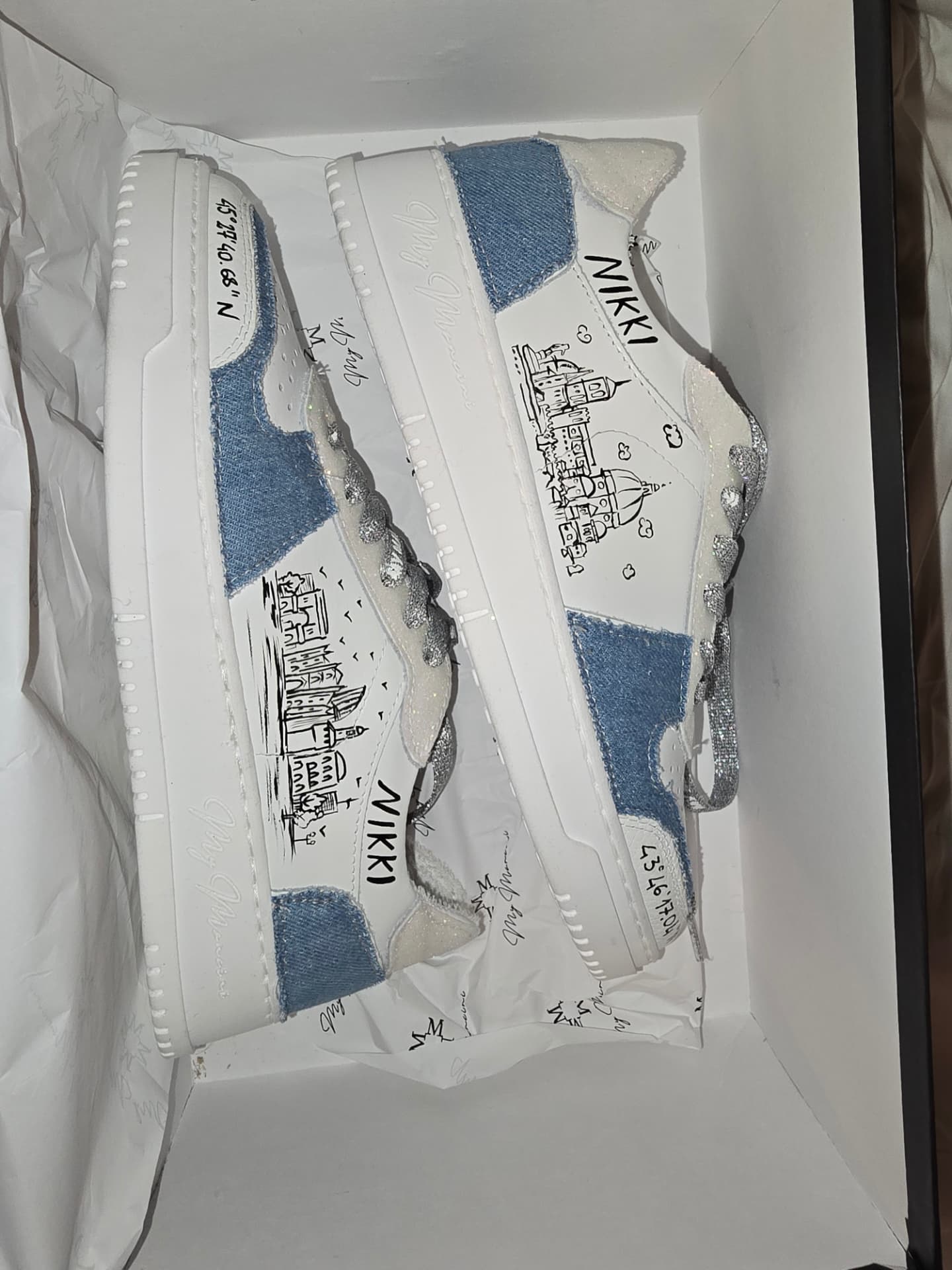 A pair of hand-painted white sneakers with Nikki’s name and Milan drawings, in their box.