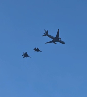 A tanker flying with two fighters against the blue sky.