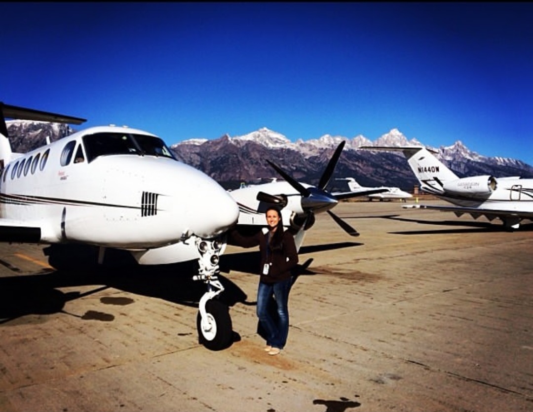 Nikki with a King Air on the ramp beneath snow-capped mountains.