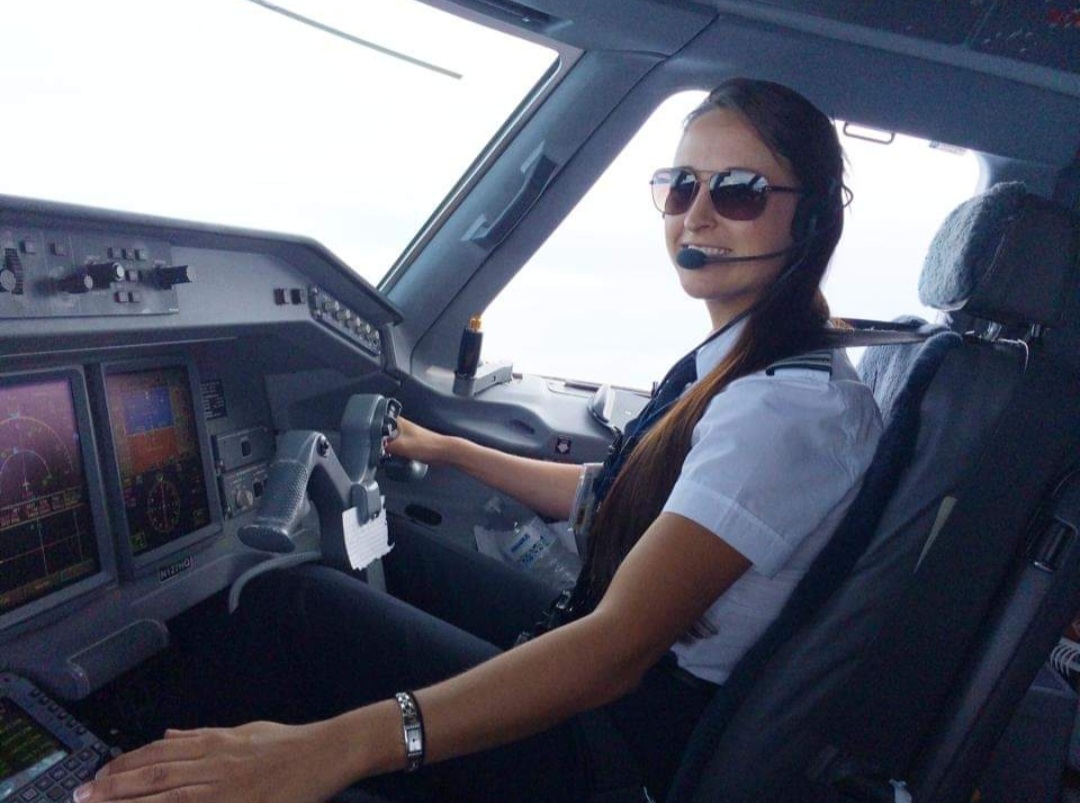 Nikki in sunglasses flying an Embraer jet.