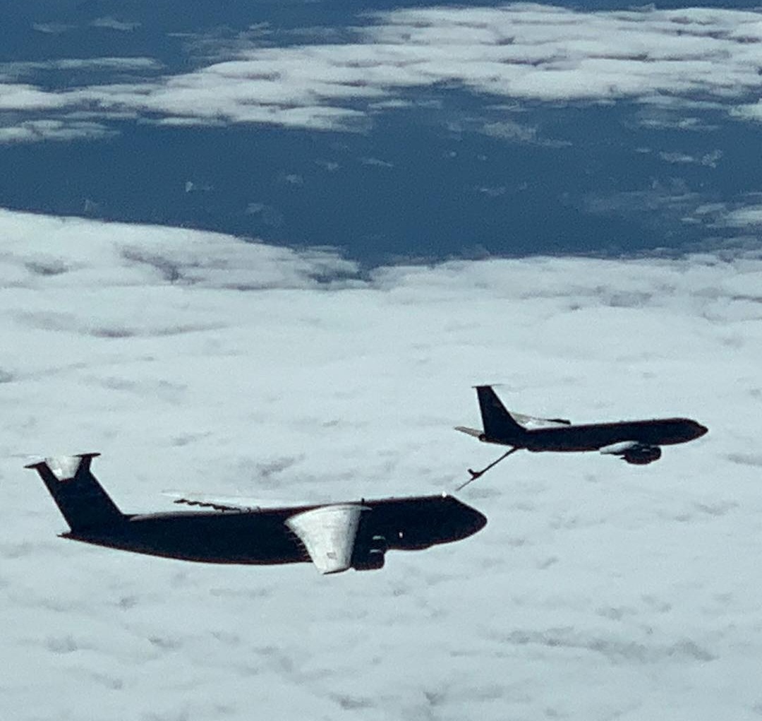 A cargo jet taking fuel from a tanker above the clouds.