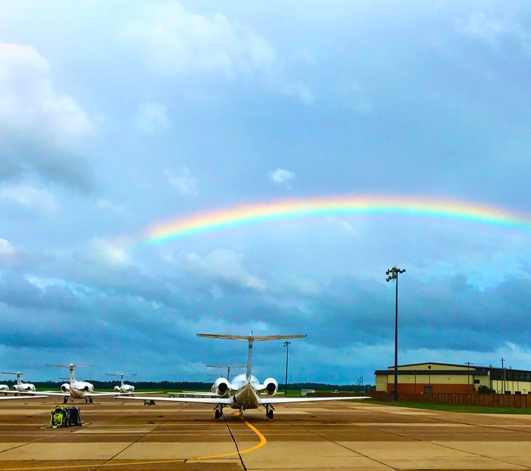 A rainbow arcing over T-1 jets on the flight line.