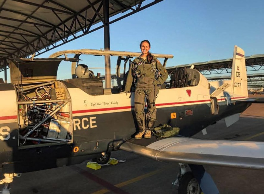 Nikki standing on the wing of a T-6 under the sunshade.