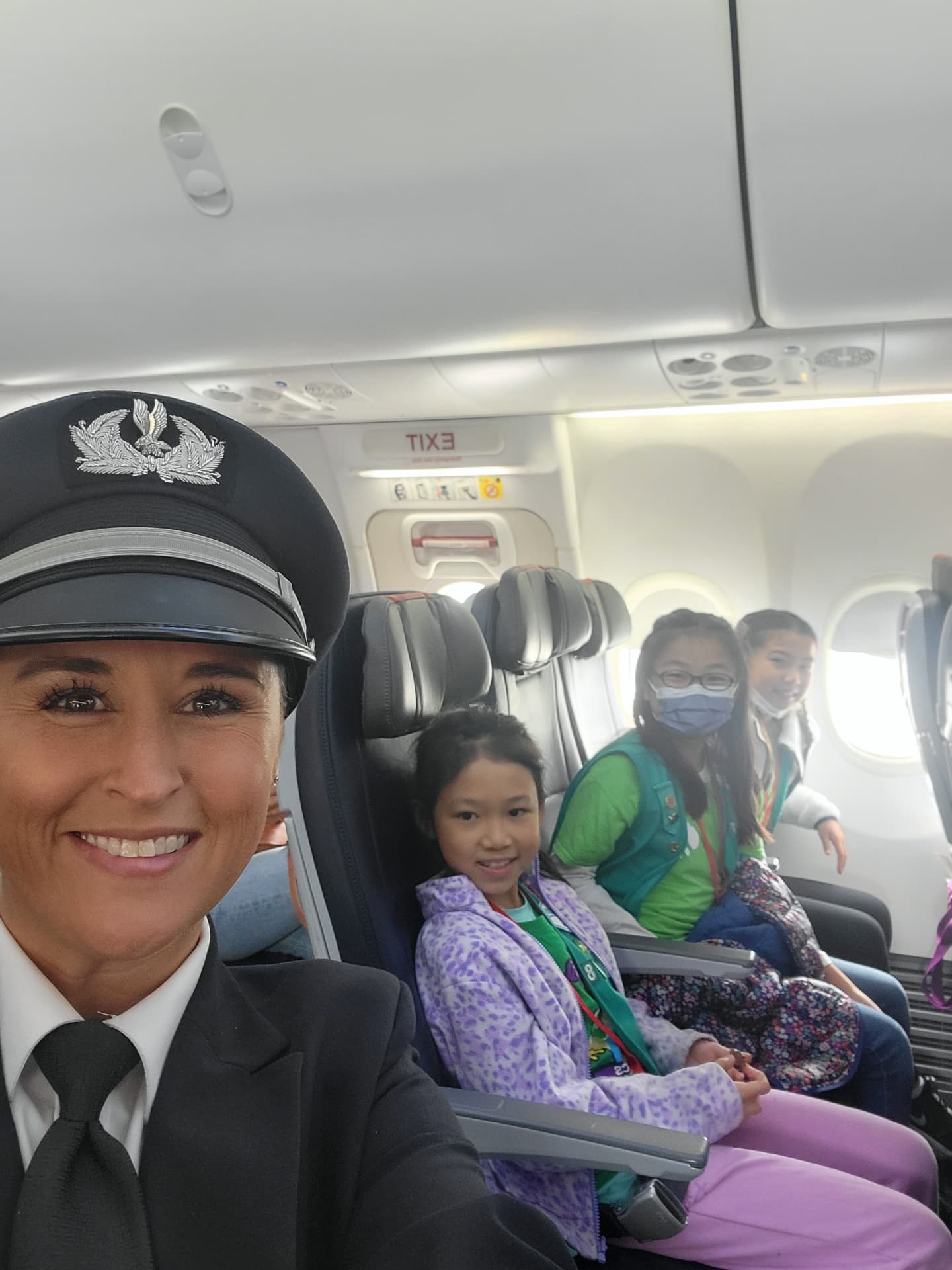 Nikki in her captain's hat with young Girl Scouts smiling from the row behind.