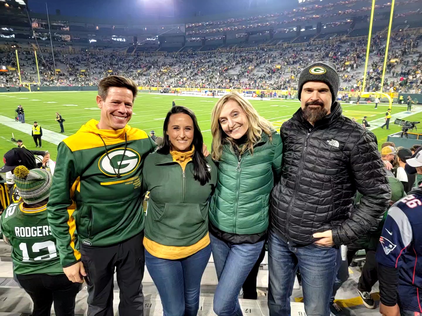 Nikki Bodie with three friends in Packers gear inside Lambeau Field at night.