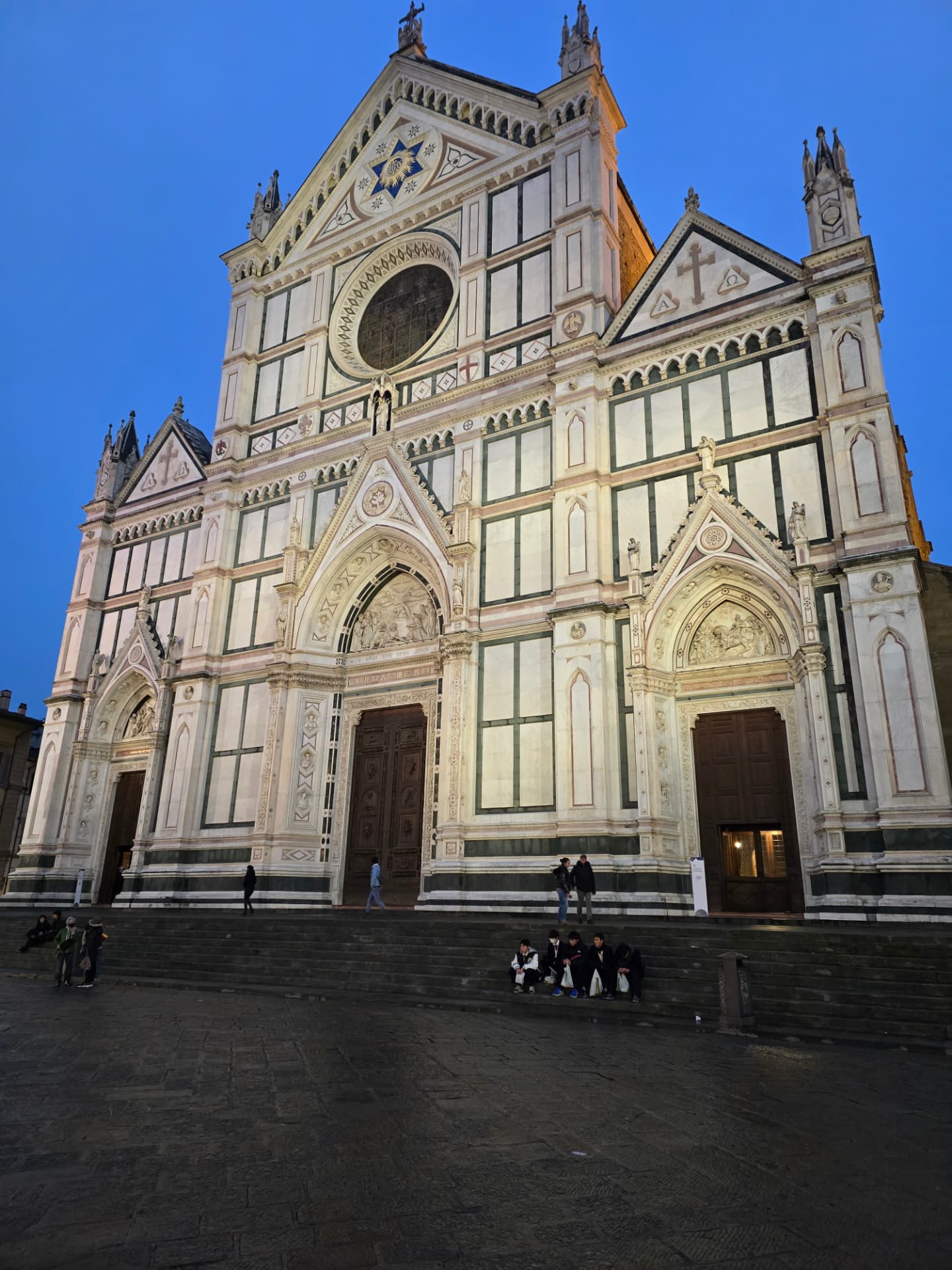 The marble façade of the Basilica of Santa Croce in Florence at dusk.