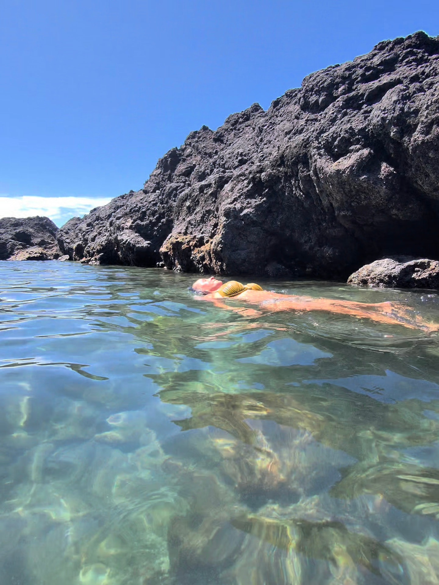 Nikki floating beside the black lava rock at Biscoitos.