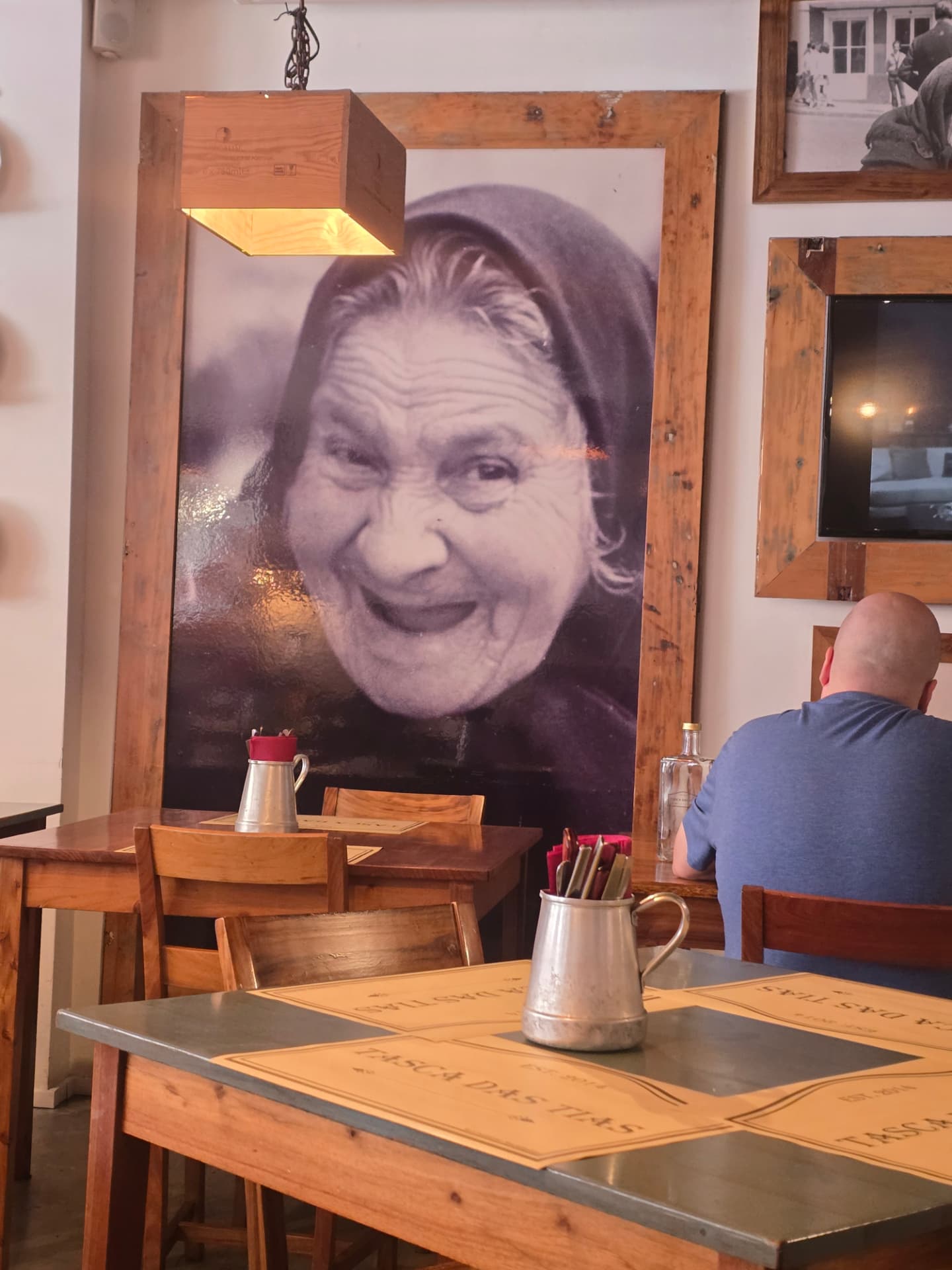 A large portrait of a laughing woman in a cloak at Tasca das Tias.